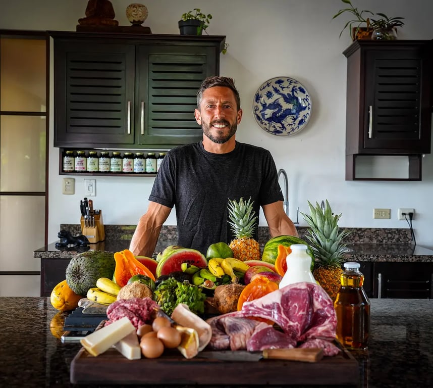 Image of Dr.Paul Saladino standing by farm fresh fruit and meat.